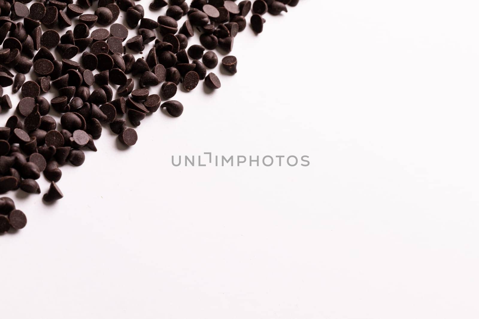 Directly above view of copy space by fresh chocolate chips over white background. unaltered, sweet food and unhealthy eating concept.