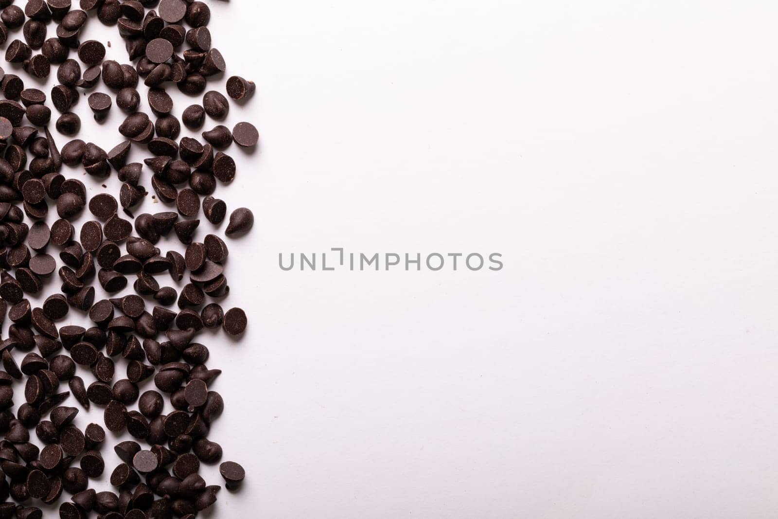 Directly above view of copy space by fresh chocolate chips on white background. unaltered, sweet food and unhealthy eating concept.