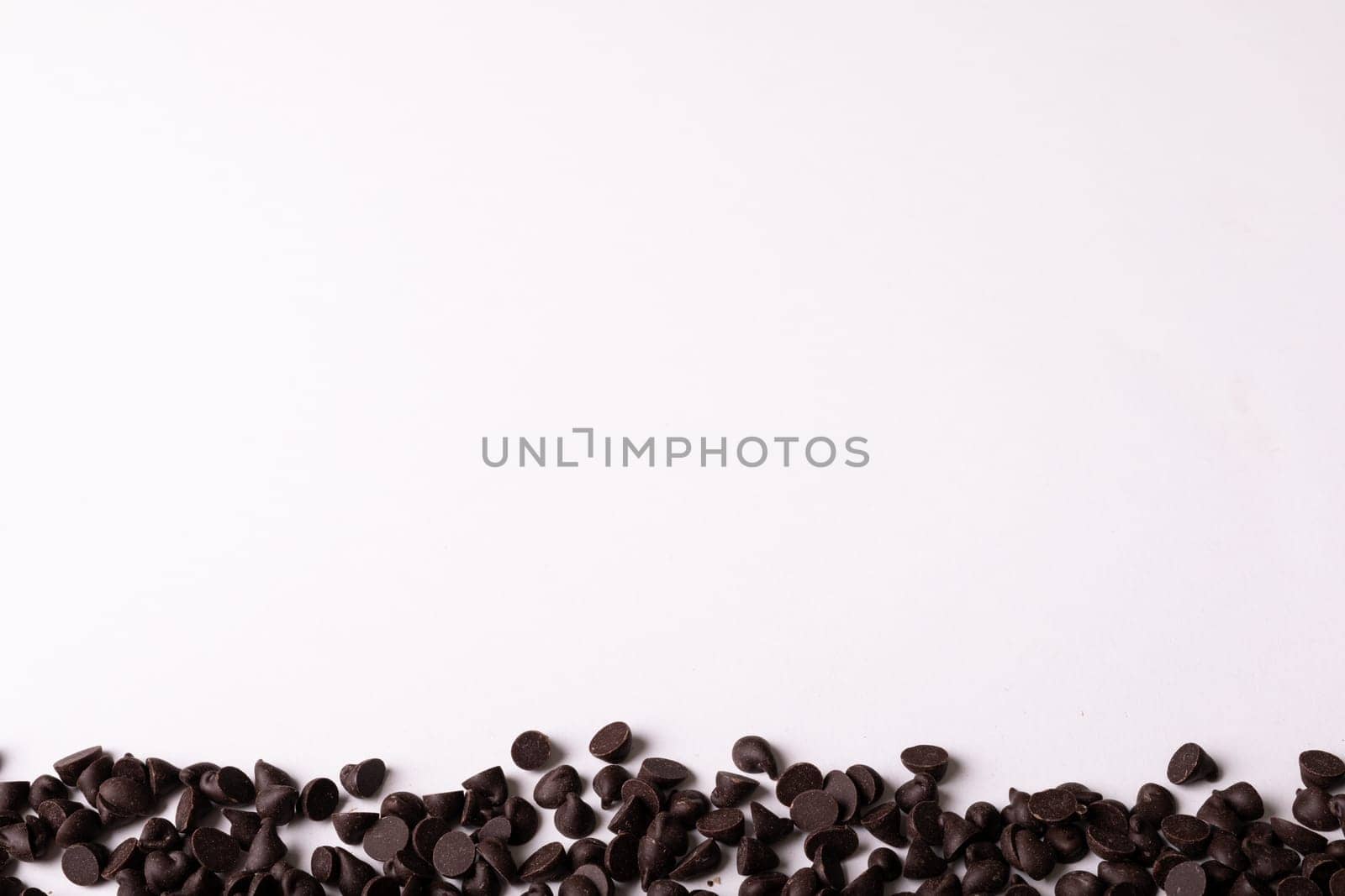 Overhead view of copy space by fresh chocolate chips on white background. unaltered, sweet food and unhealthy eating concept.