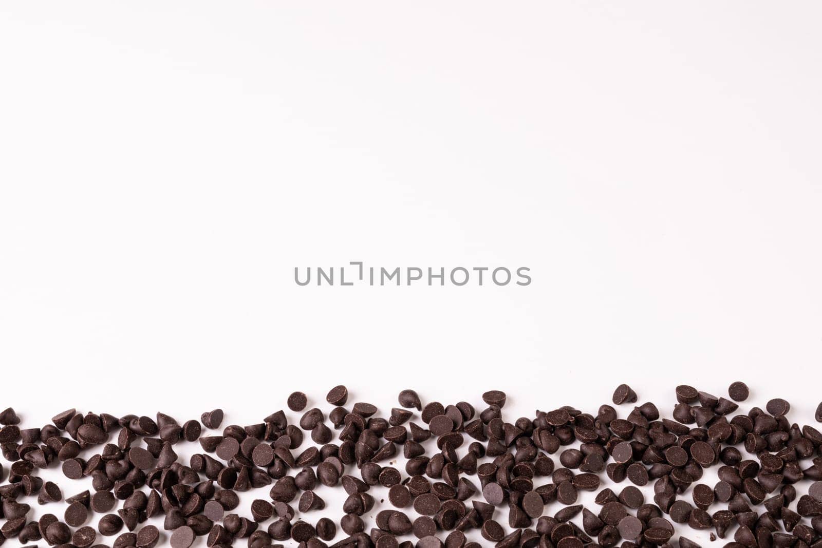 Overhead view of fresh chocolate chips on white background with copy space by Wavebreakmedia