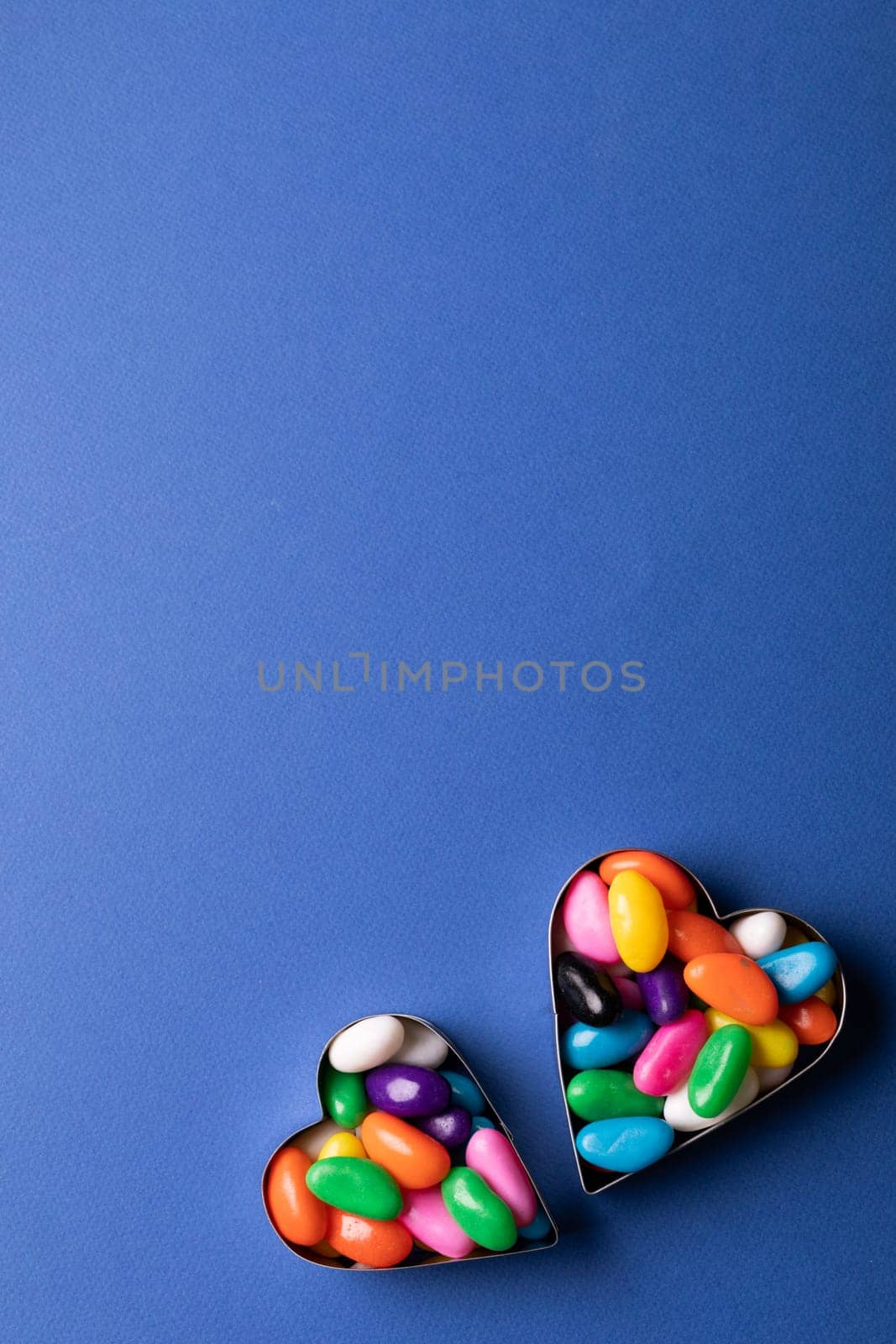 Overhead view of copy space above colorful candies in heart shape containers over blue background by Wavebreakmedia