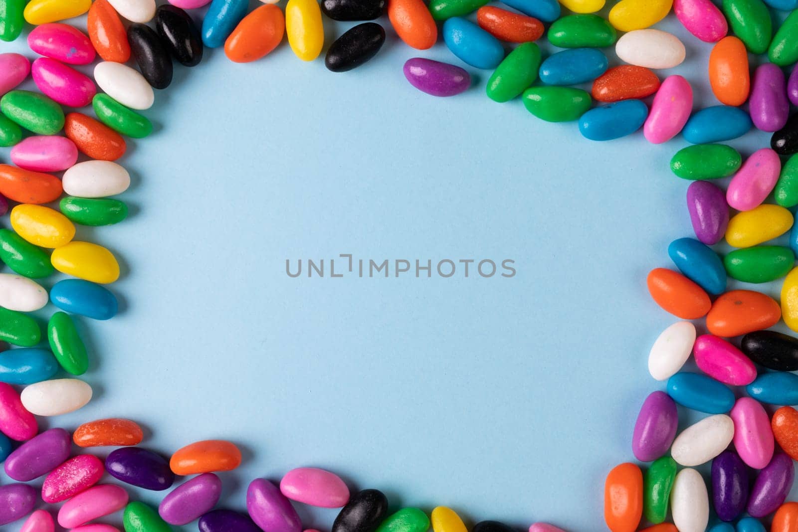 Directly above view of copy space amidst multi colored candies on blue background. unaltered, sweet food and unhealthy eating concept.