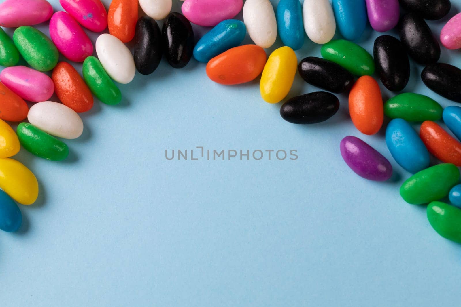 Directly above view of colorful candies and copy space on blue background. unaltered, sweet food and unhealthy eating concept.