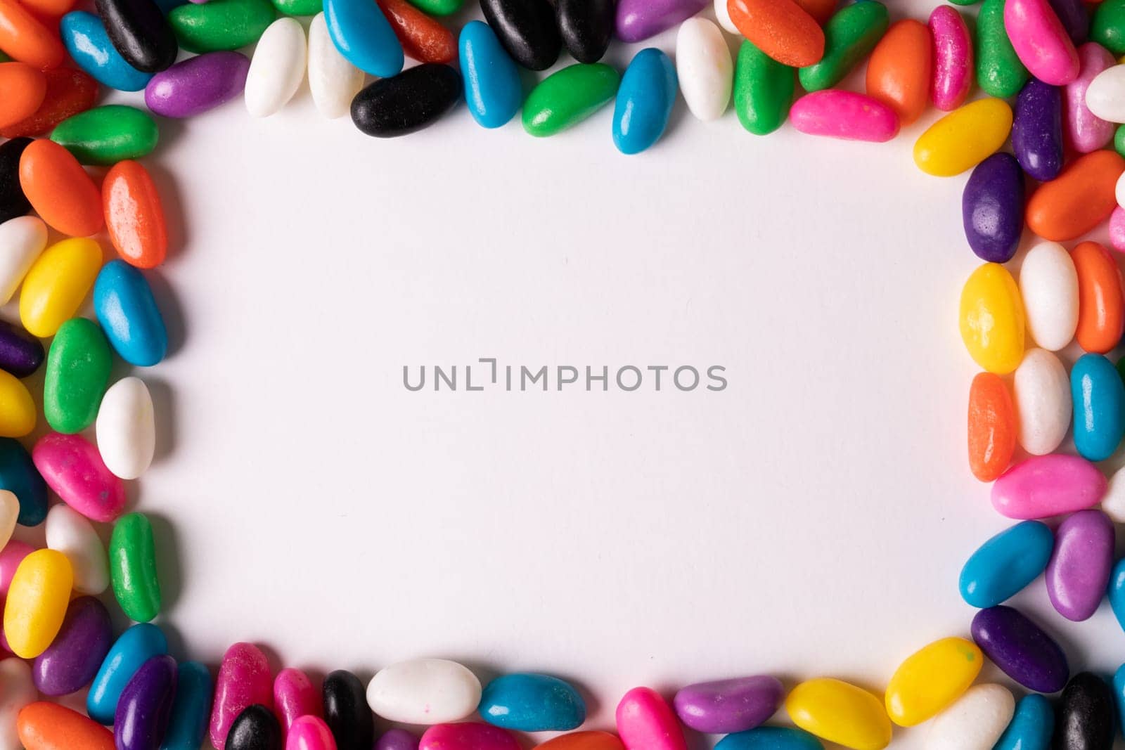 Directly above view of copy space amidst multi colored candies over white background by Wavebreakmedia