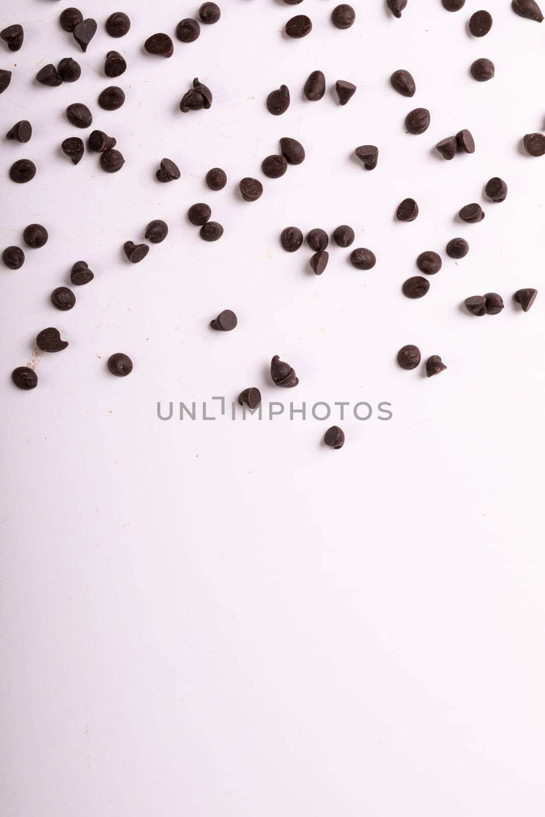 Directly above view of fresh chocolate chips scattered over copy space on white background. unaltered, sweet food and unhealthy eating concept.