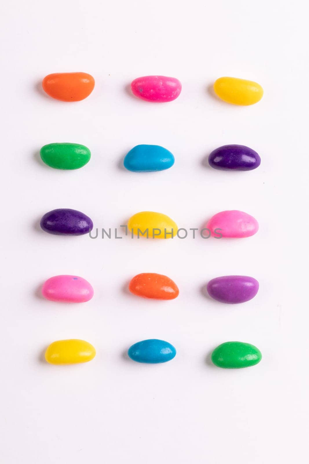 Directly above view of multi colored candies arranged in a row over white background by Wavebreakmedia