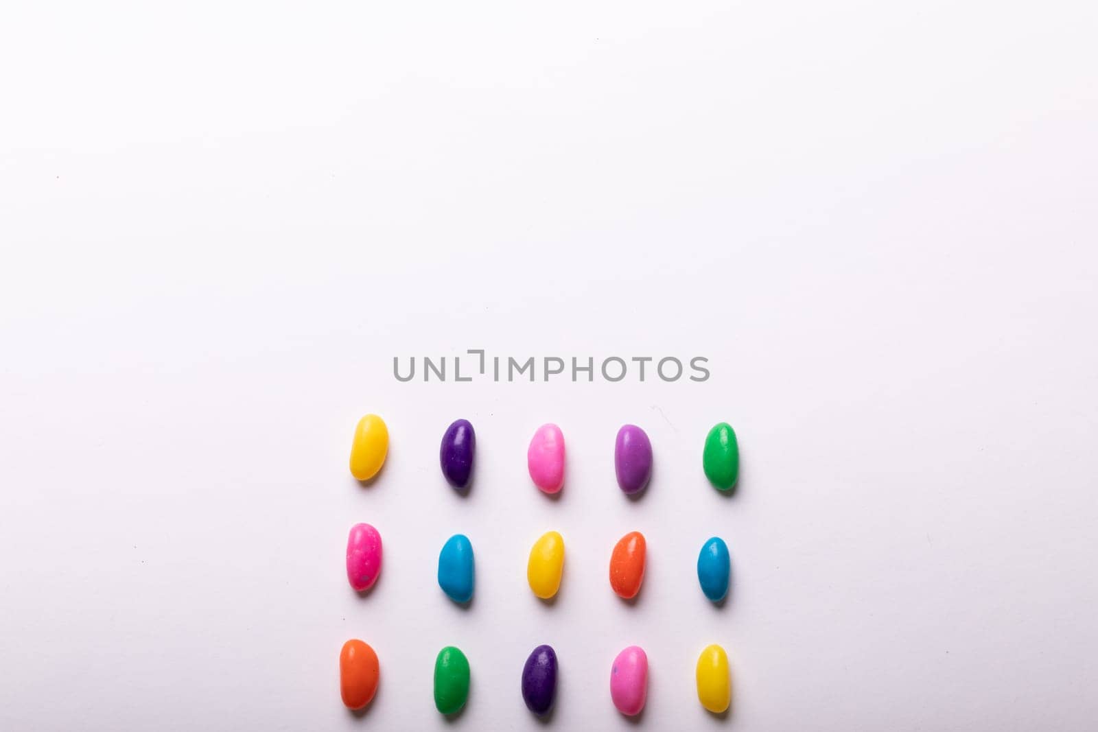 Directly above view of multi colored candies by copy space over white background by Wavebreakmedia