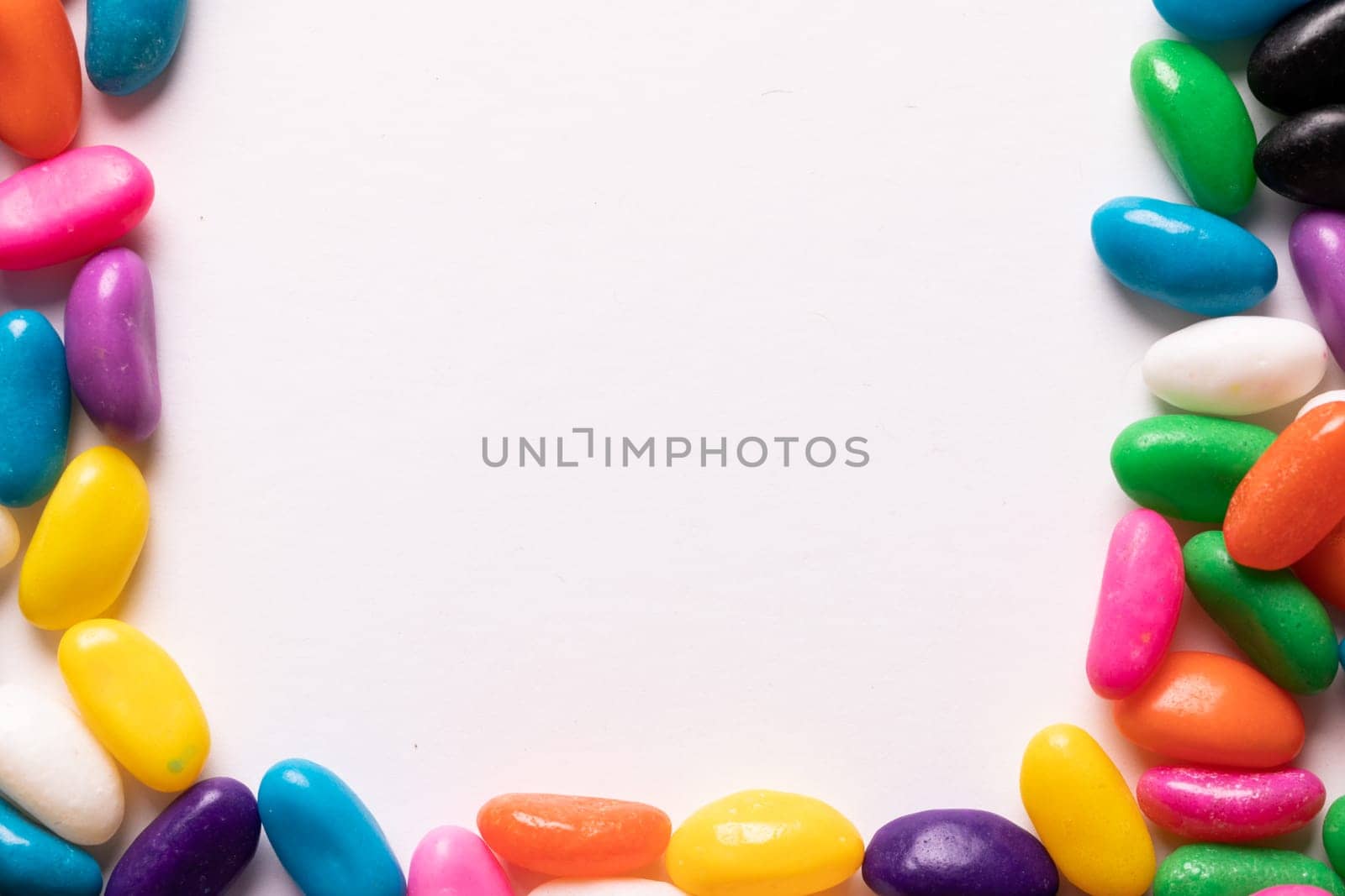 Directly above view of copy space amidst multi colored candies over white background. unaltered, sweet food and unhealthy eating concept.