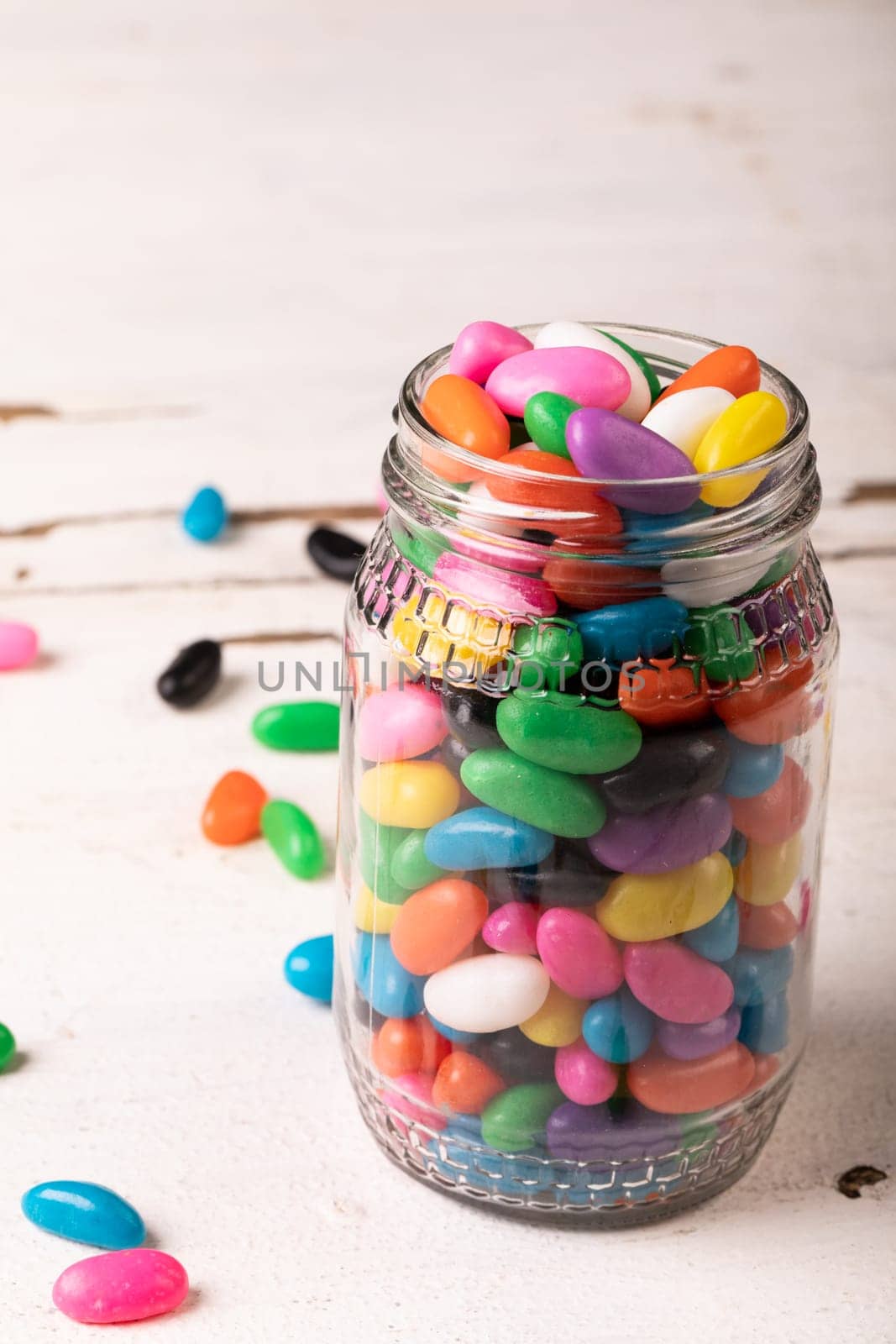 Close-up of multi colored candies in glass jar against white background by Wavebreakmedia