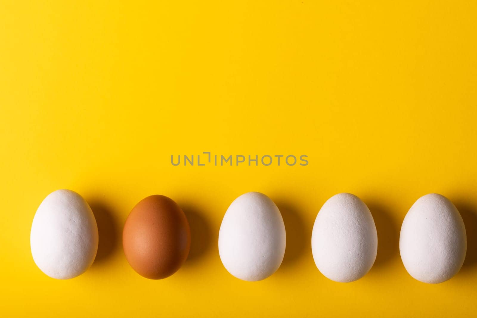 Overhead view of brown egg amidst whites arranged side by side with copy space on yellow background by Wavebreakmedia