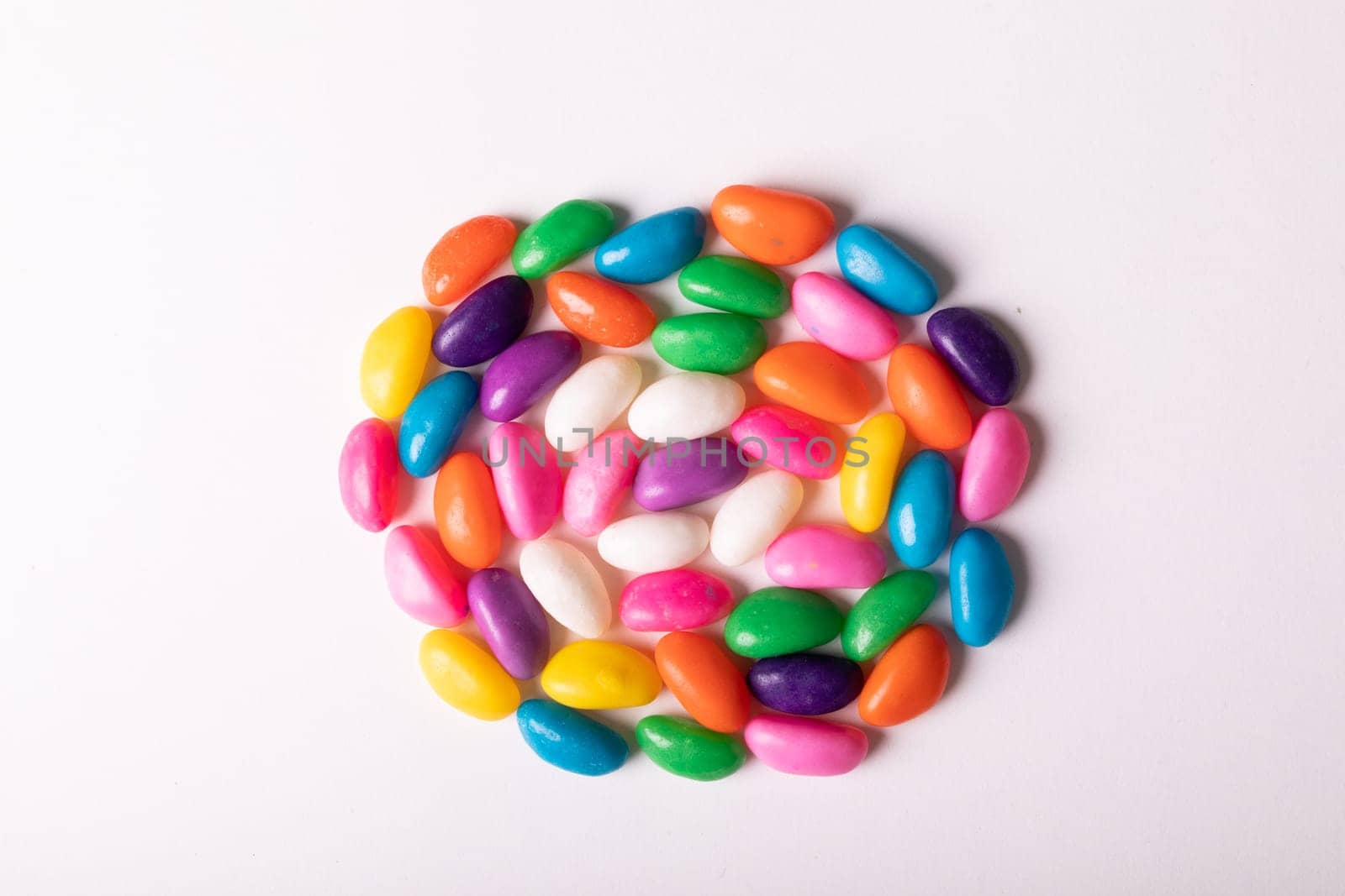 Overhead view of multi colored candies arranged in circle over white background with copy space. unaltered, sweet food and unhealthy eating concept.
