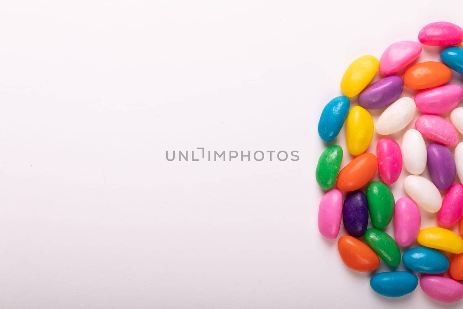 Directly above view of colorful candies arranged in semi-circle by copy space on white background by Wavebreakmedia