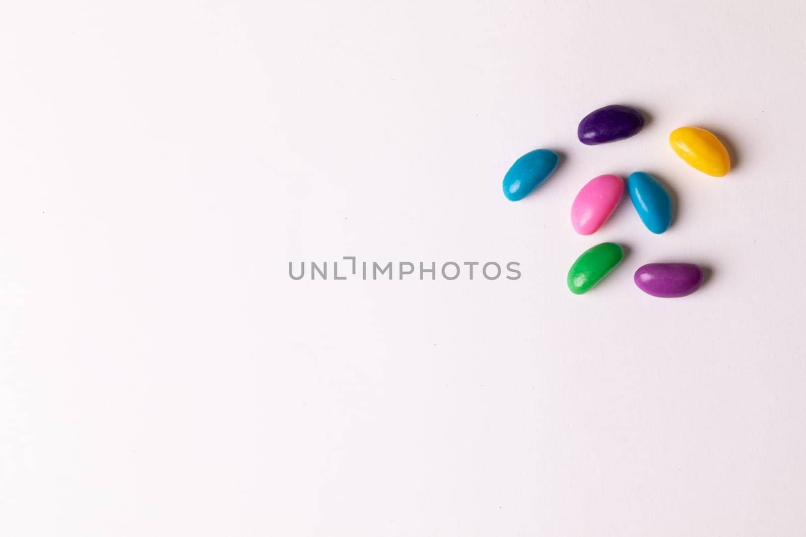 Directly above view of colorful sweet candies by copy space against white background by Wavebreakmedia