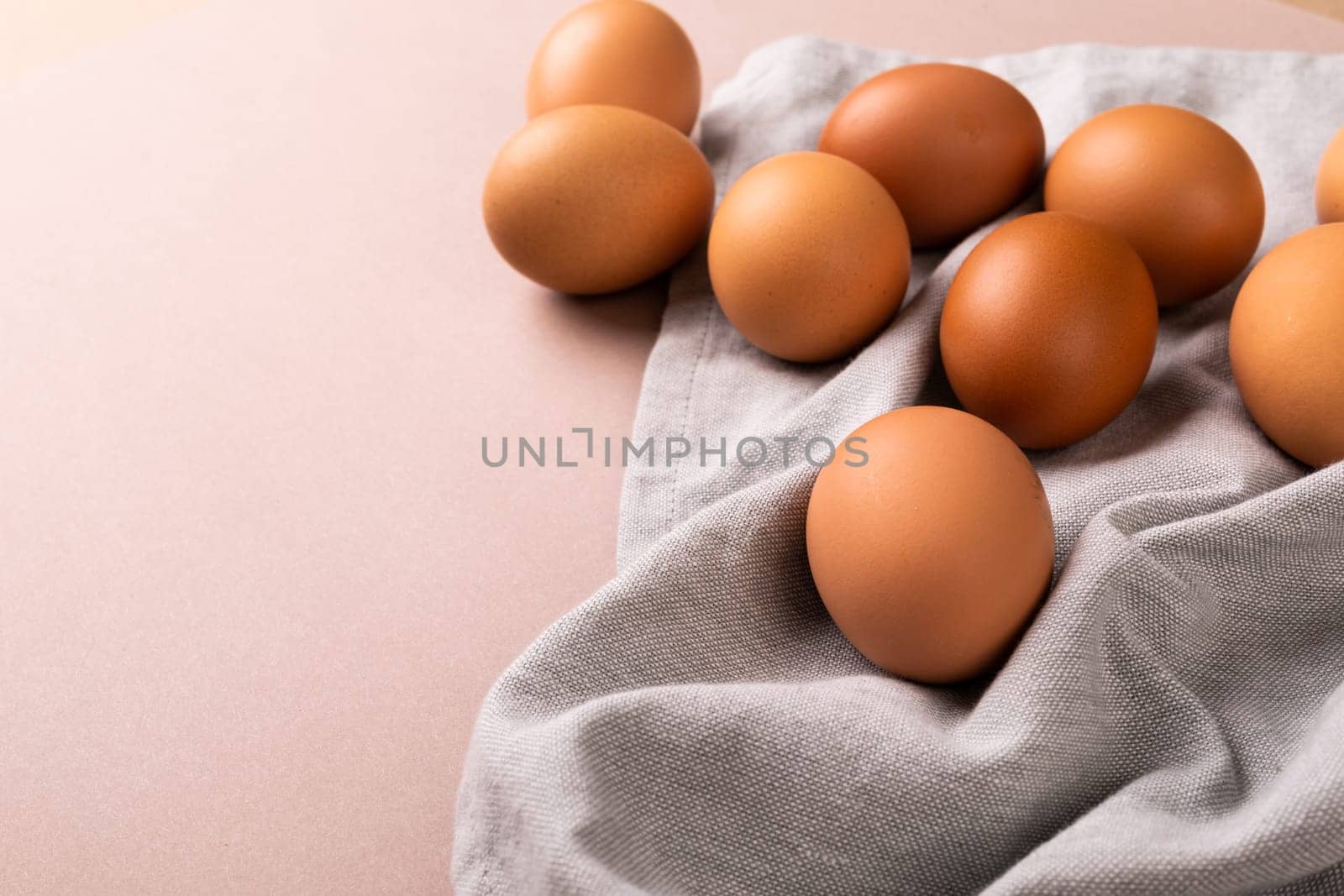 High angle view of fresh brown eggs on napkin by copy space over pink background. unaltered, food, healthy eating concept.