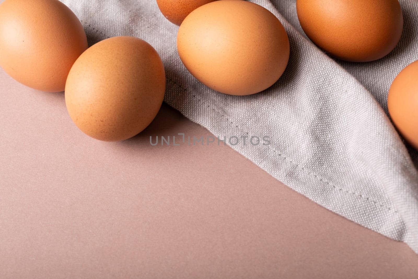 Close-up high angle view of fresh brown eggs and gray napkin over colored background with copy space by Wavebreakmedia