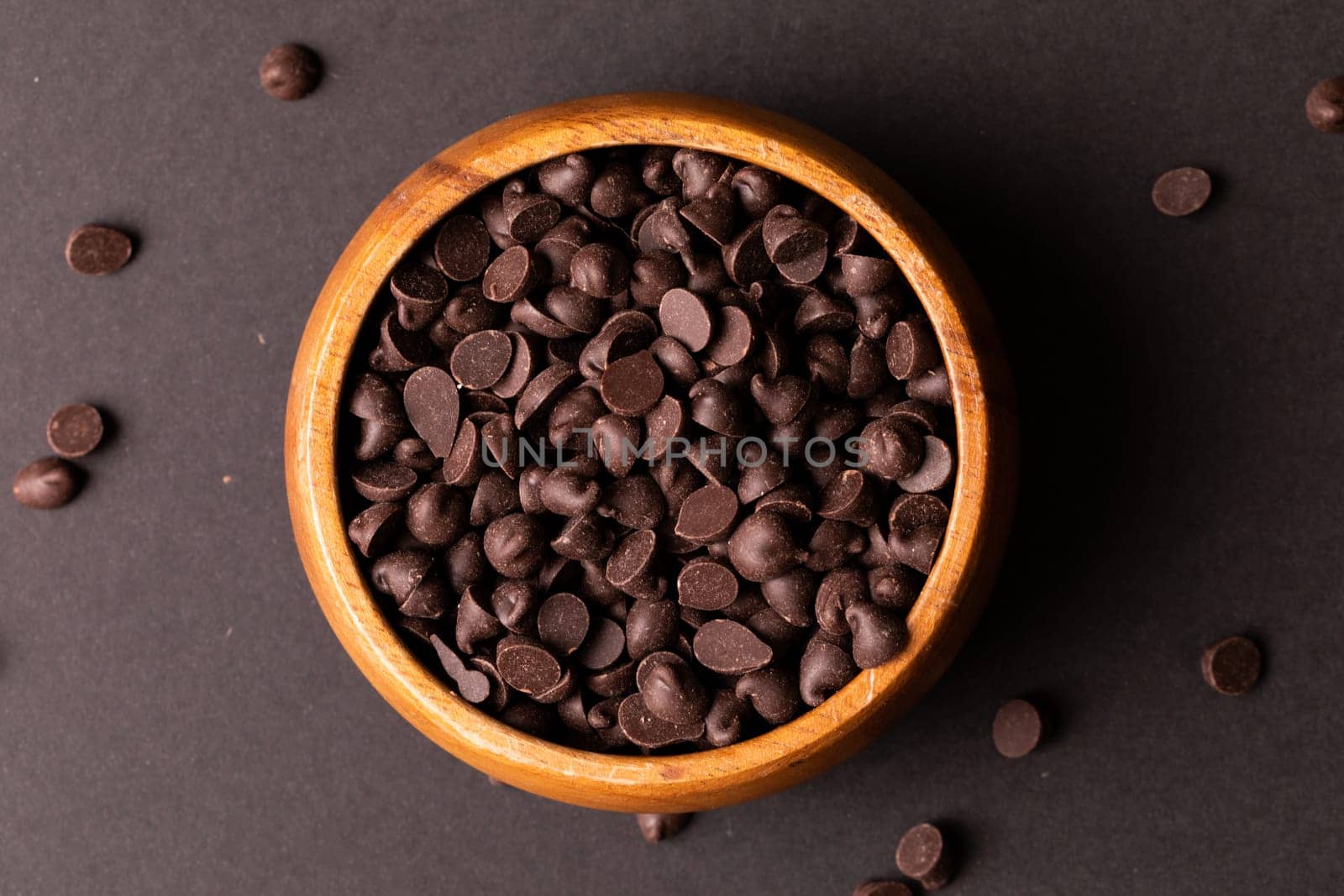 Directly above view of fresh chocolate chips in wooden bowl over colored background by Wavebreakmedia