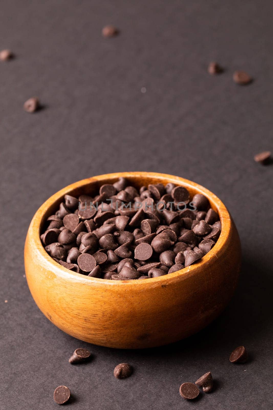 High angle view of fresh chocolate chips in wooden bowl against colored background by Wavebreakmedia