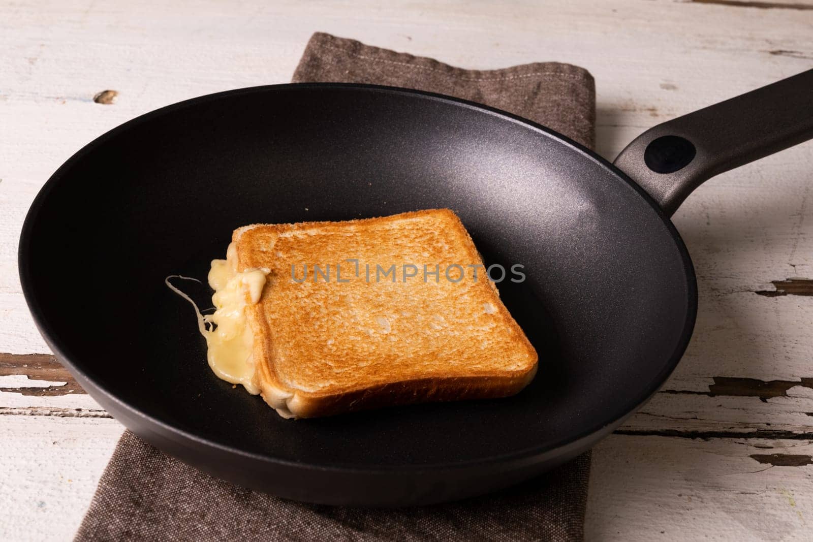 High angle view of fresh cheese sandwich in cooking pan on napkin over white table. unaltered, food, unhealthy eating and snack concept.