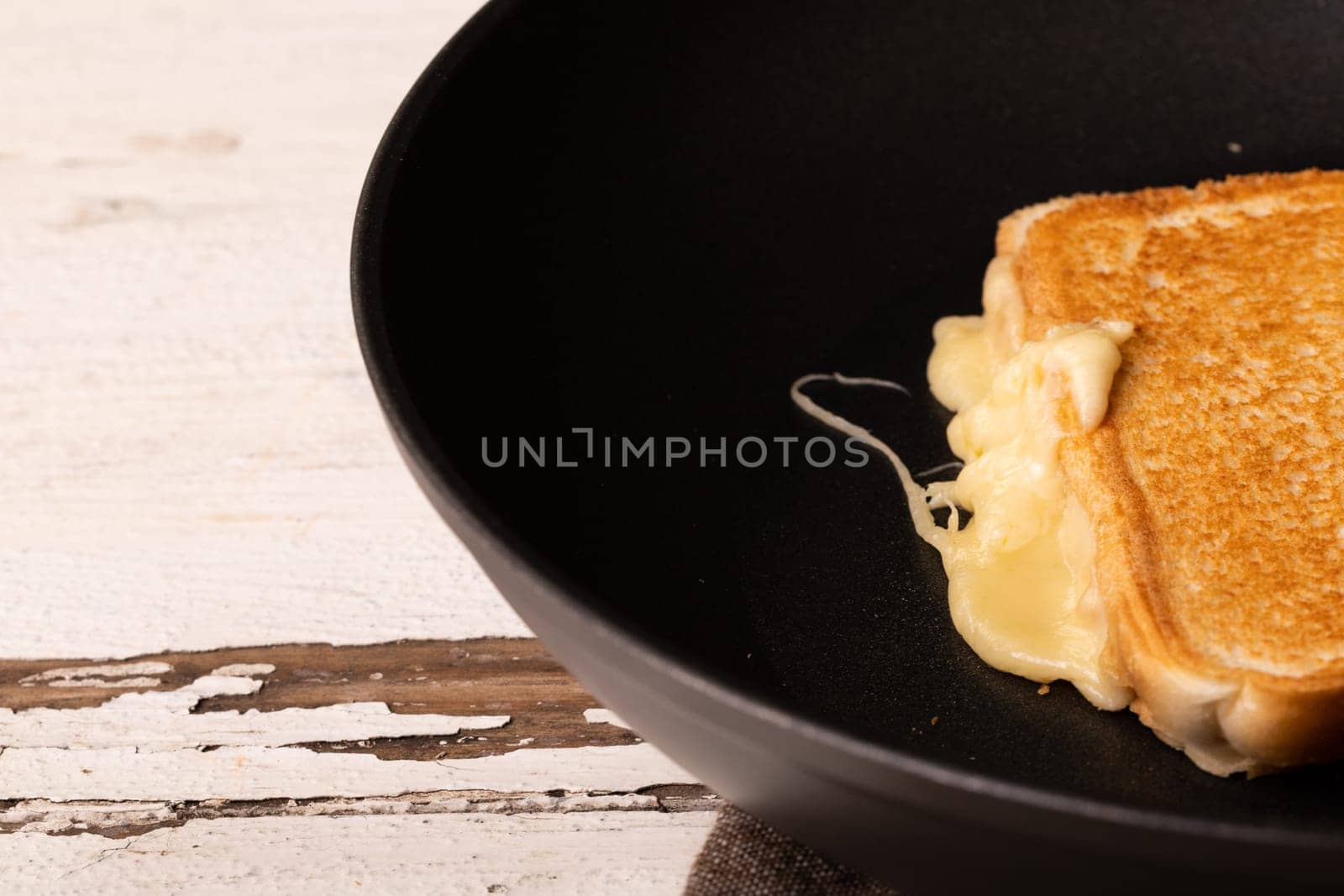 High angle view of fresh melting cheese sandwich in cooking pan on white table by Wavebreakmedia