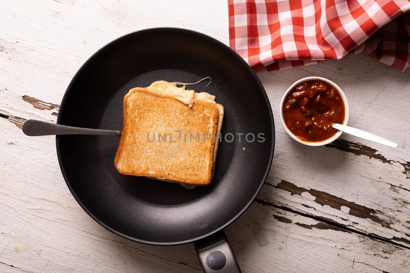 Directly above view of fresh cheese sandwich in cooking pan by dip bowl on wooden table by Wavebreakmedia
