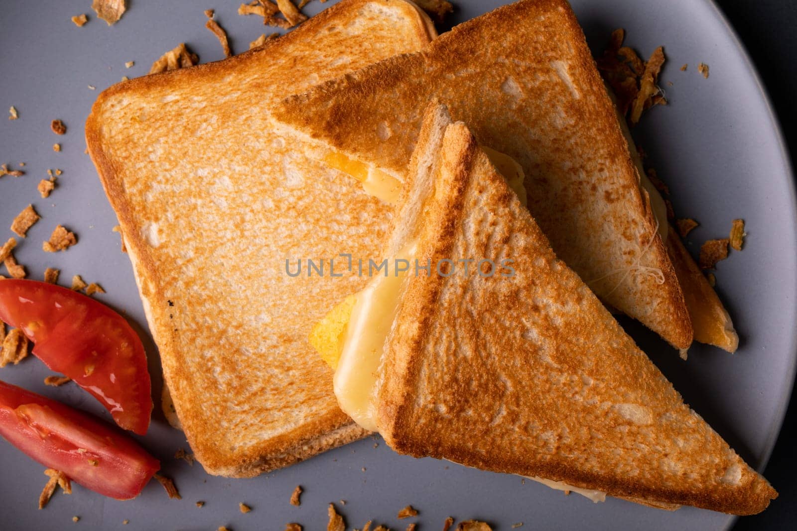 Directly above view of fresh cheese toast sandwich served with tomato slices served in plate by Wavebreakmedia