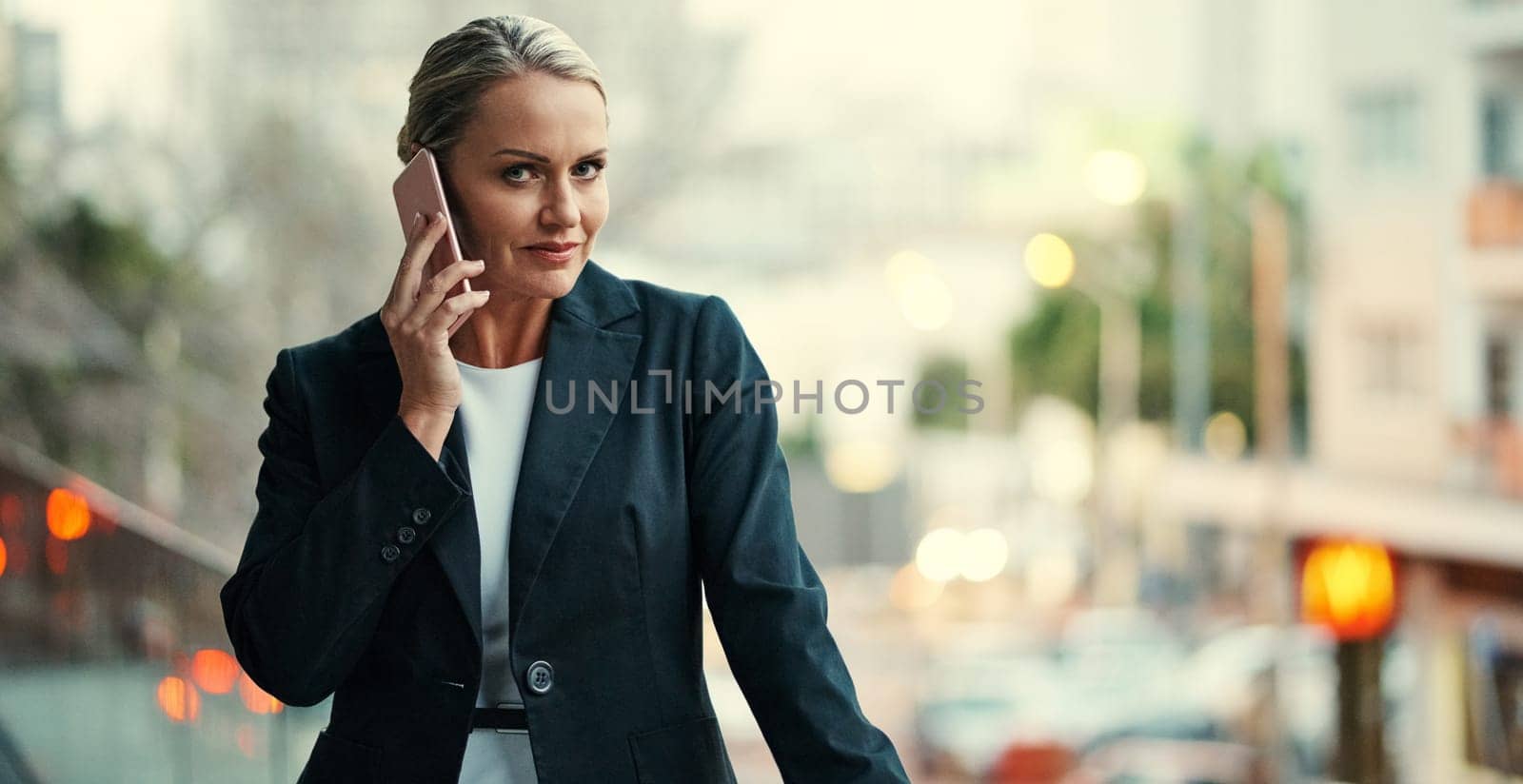 Communication is a key part of success. Cropped portrait of an attractive mature businesswoman using her cellphone while standing on the balcony of her office. by YuriArcurs