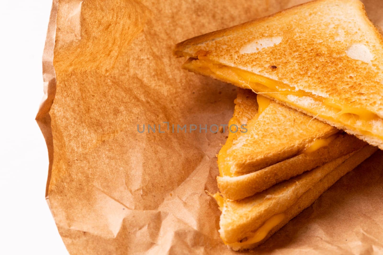 Close-up of fresh cheese toast sandwich on brown wax paper. unaltered, food, unhealthy eating and snack concept.
