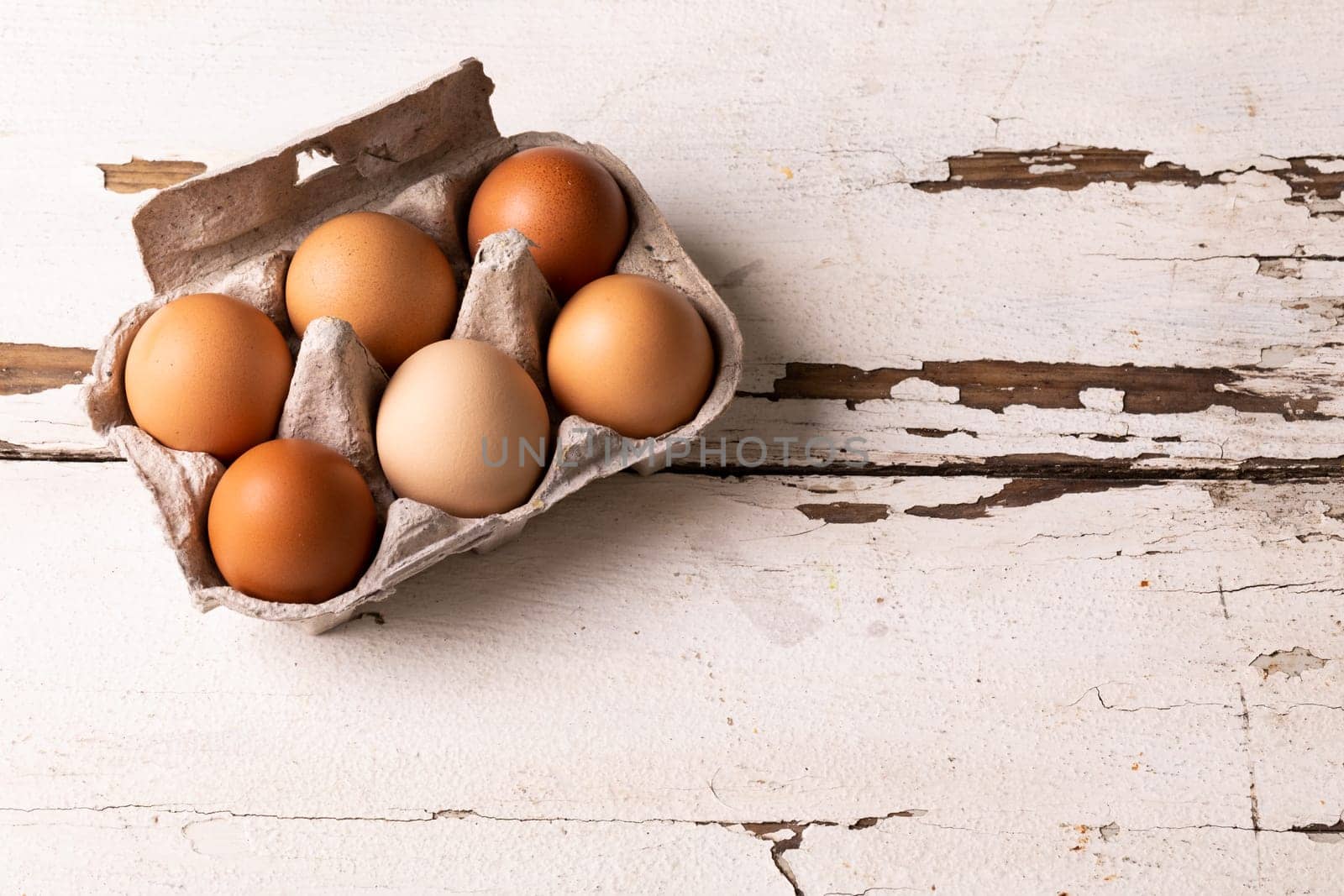 High angle view of fresh brown eggs in carton on white wooden table. unaltered, food, healthy eating and organic concept.