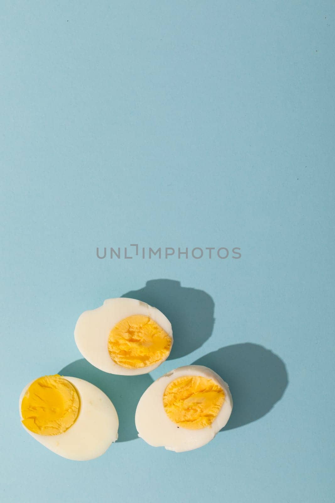 Directly above view of copy space with fresh boiled white egg halves over blue background by Wavebreakmedia