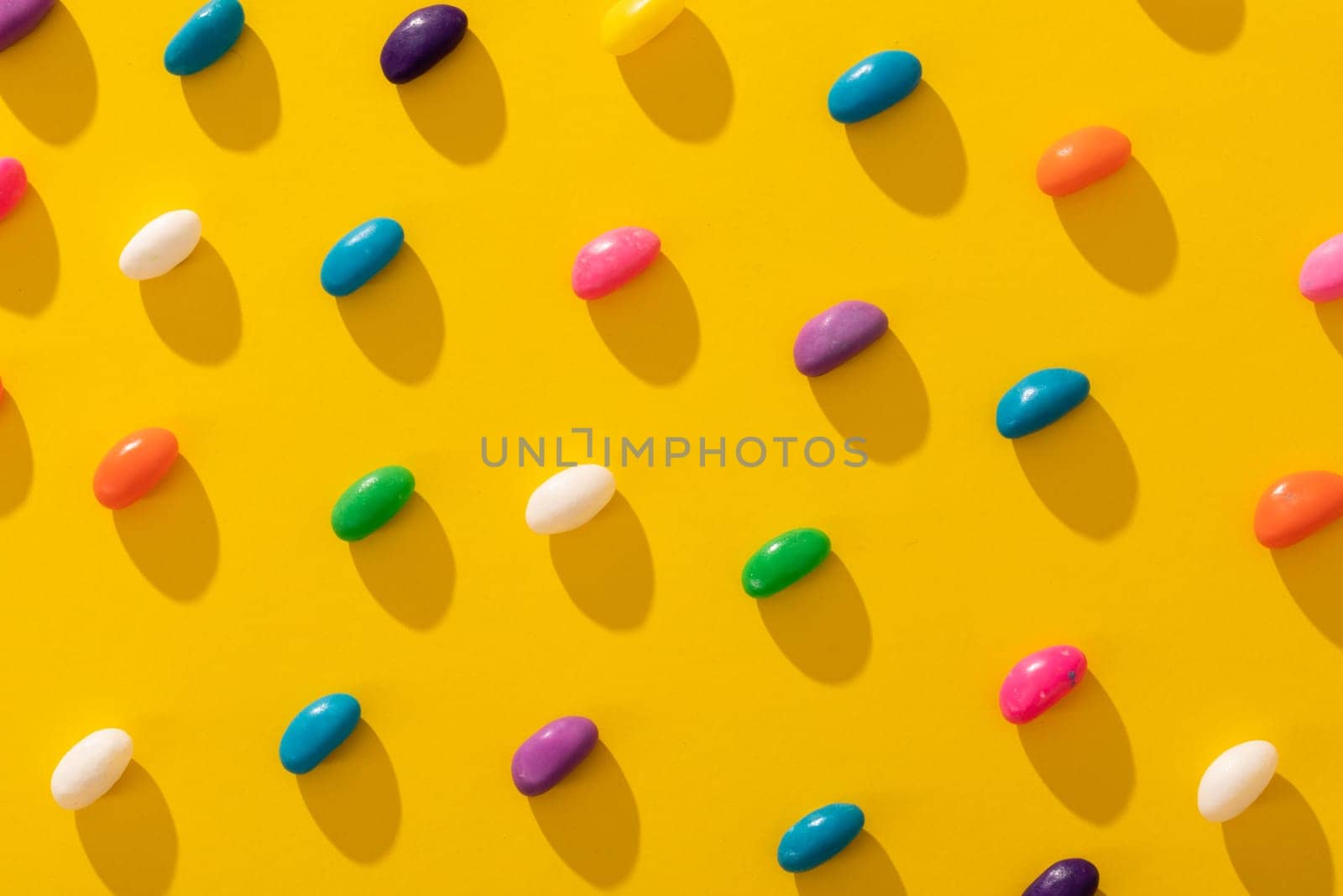 Full frame shot of multi colored candies arranged in a row on yellow background by Wavebreakmedia