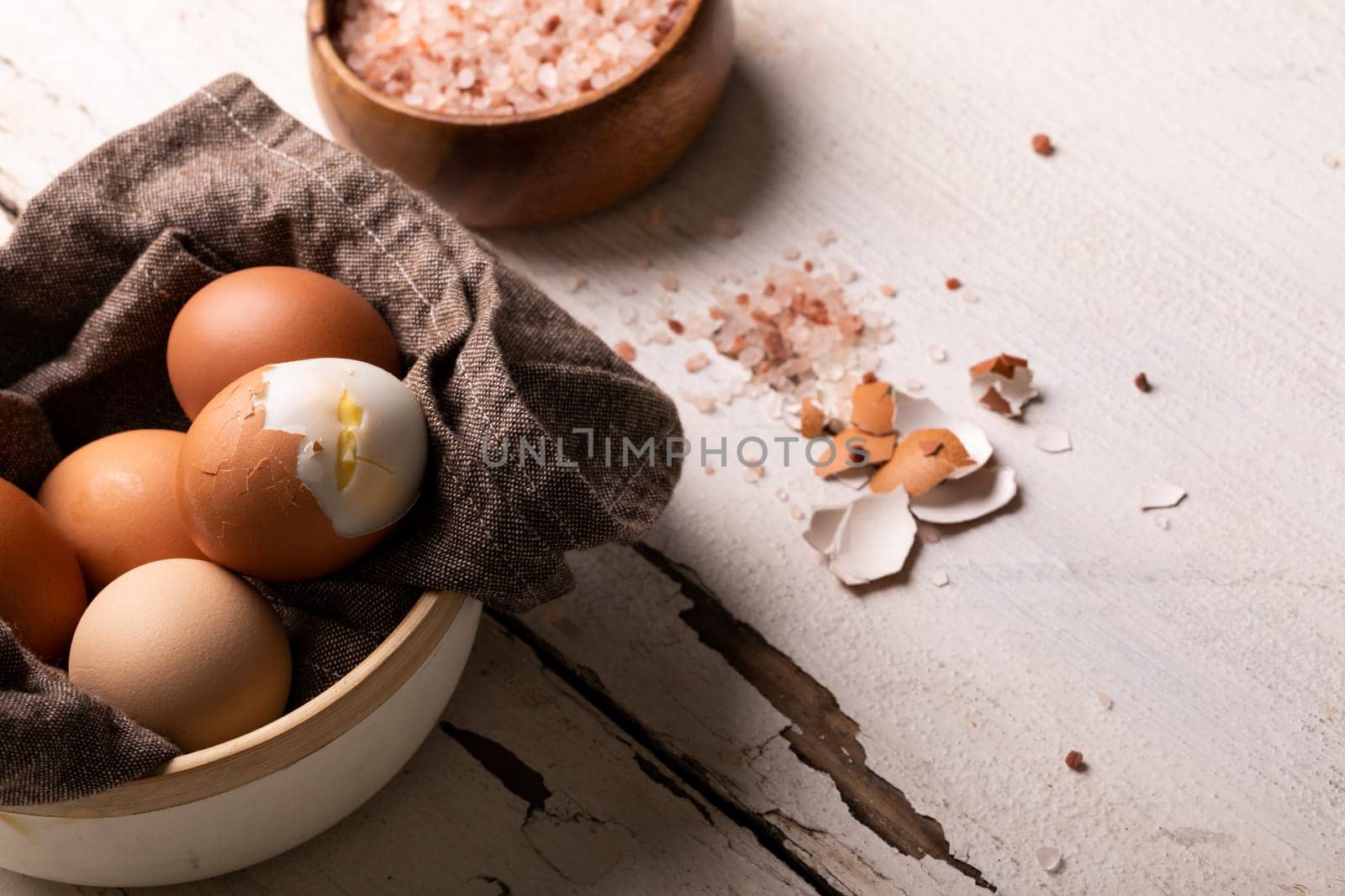 High angle view of fresh boiled brown eggs in bowl by rock salt on white table. unaltered, food, healthy eating and organic concept.