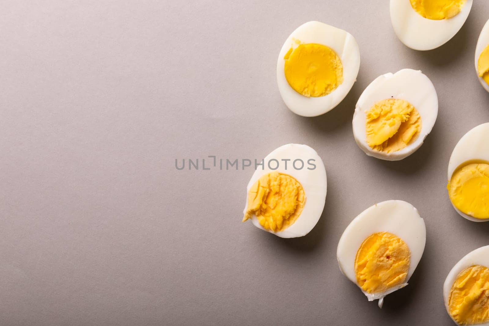 Directly above view of fresh white eggs boiled with yellow yolks by copy space on gray background. unaltered, food, healthy eating and organic concept.