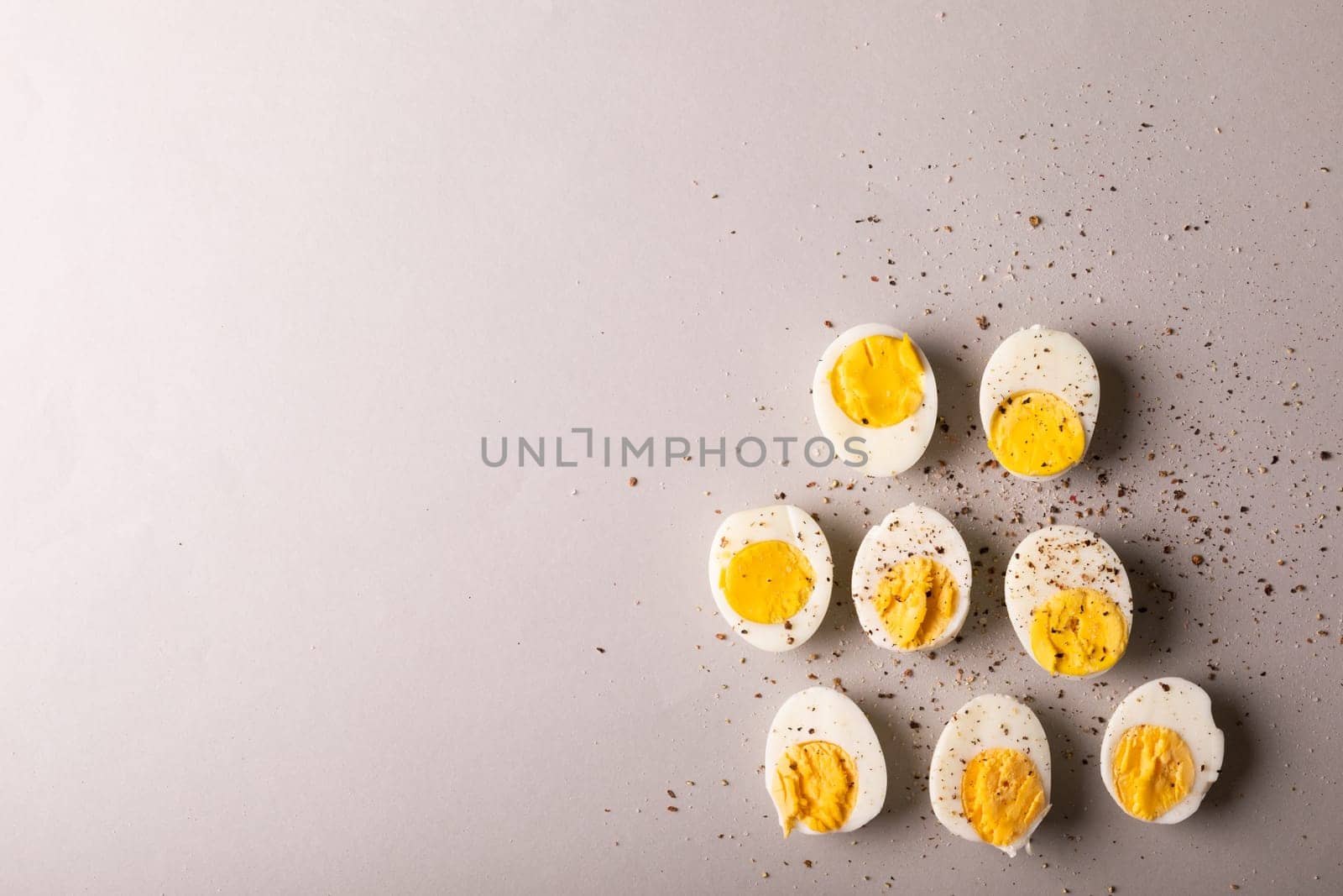 Overhead view of peppercorn seasoning on boiled white eggs by copy space on gray background. unaltered, food, healthy eating and organic concept.