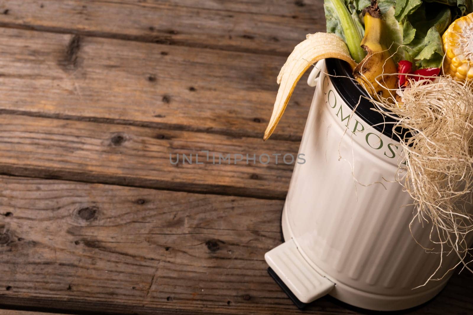 High angle view of organic waste in white compost bin on wooden table by Wavebreakmedia