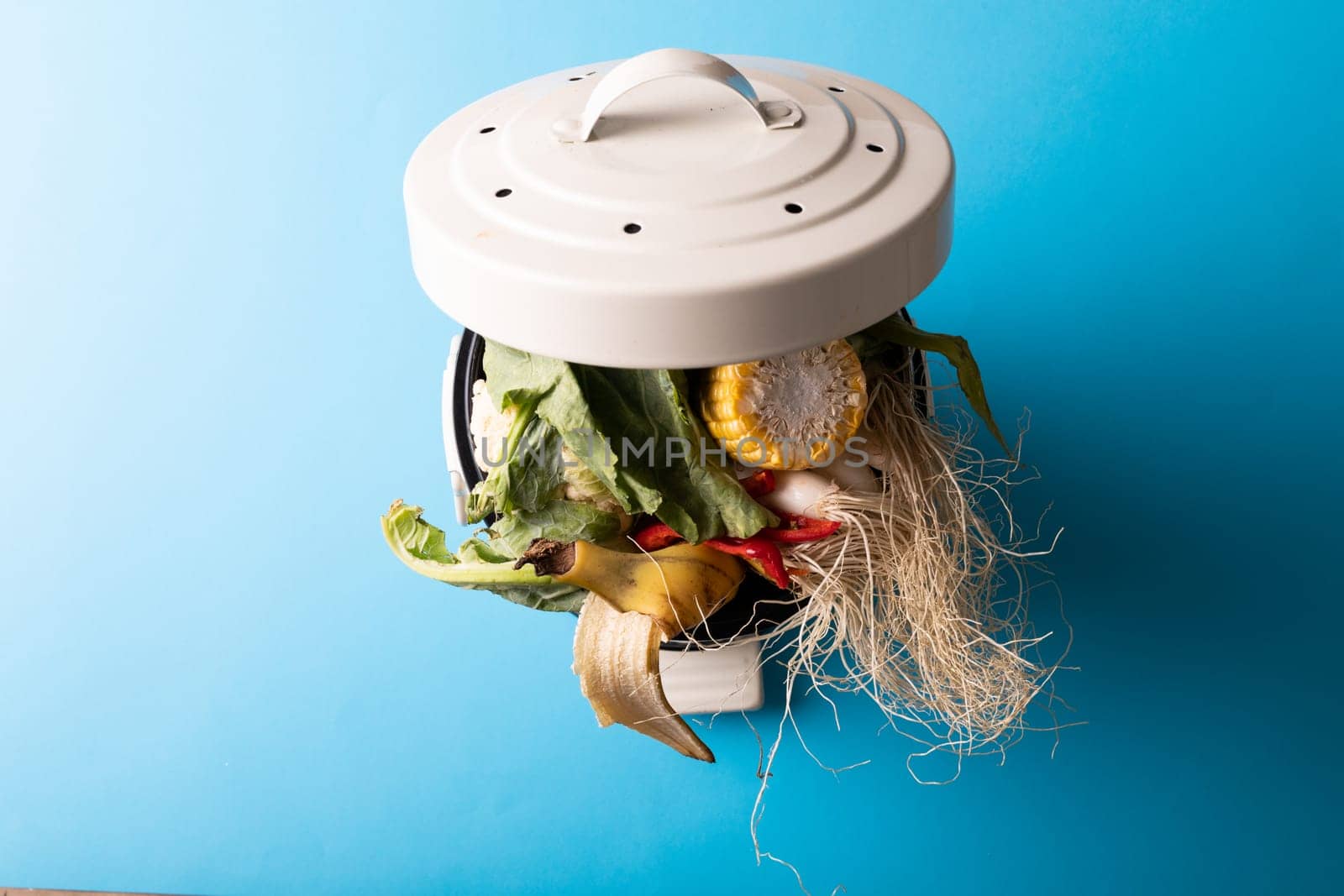 High angle view of overload organic waste in compost bin over blue background by Wavebreakmedia