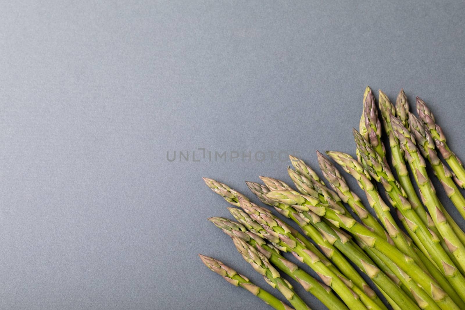 Directly above view of fresh green asparagus on gray background with copy space by Wavebreakmedia