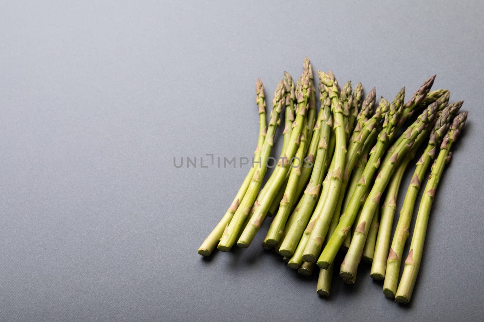 High angle view of fresh green asparagus on gray background with copy space by Wavebreakmedia