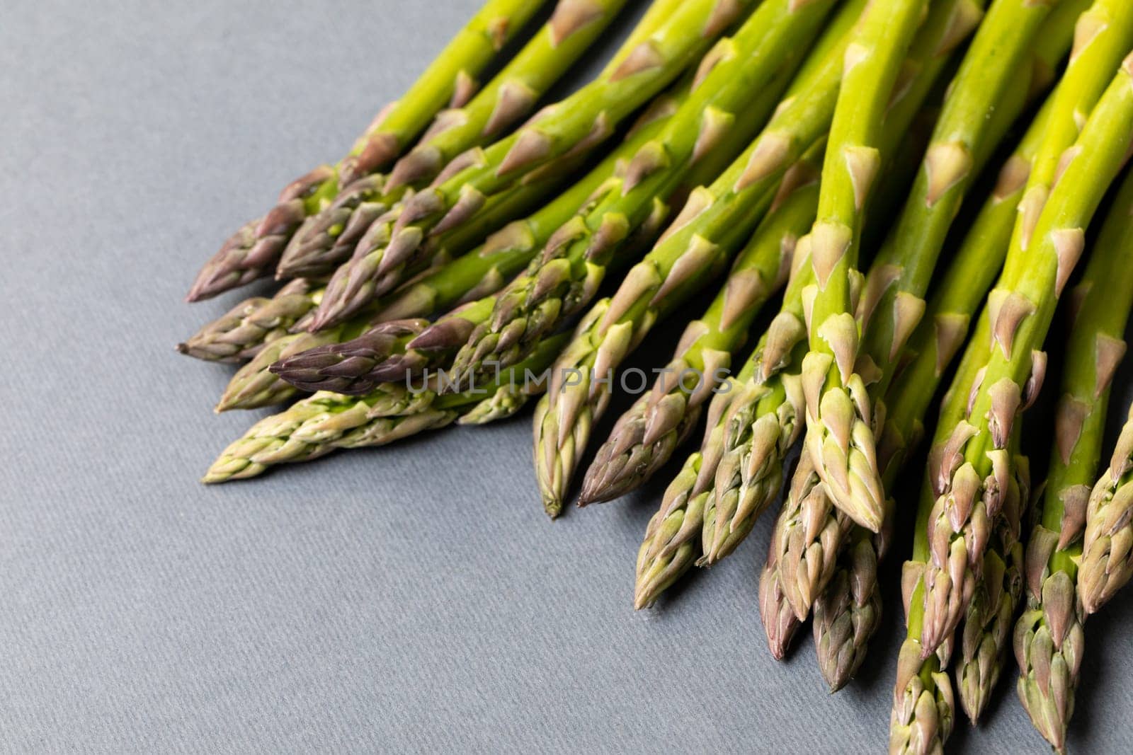 High angle close-up view of fresh asparagus over gray background. unaltered, food, healthy eating and organic concept.