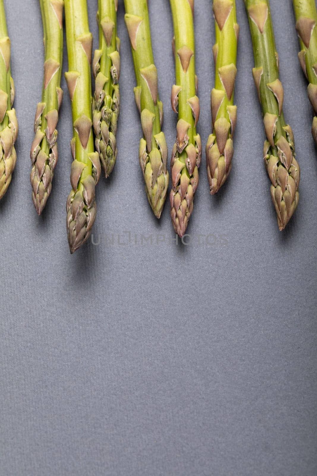 Directly above close-up view of fresh green asparagus over copy space on gray background by Wavebreakmedia