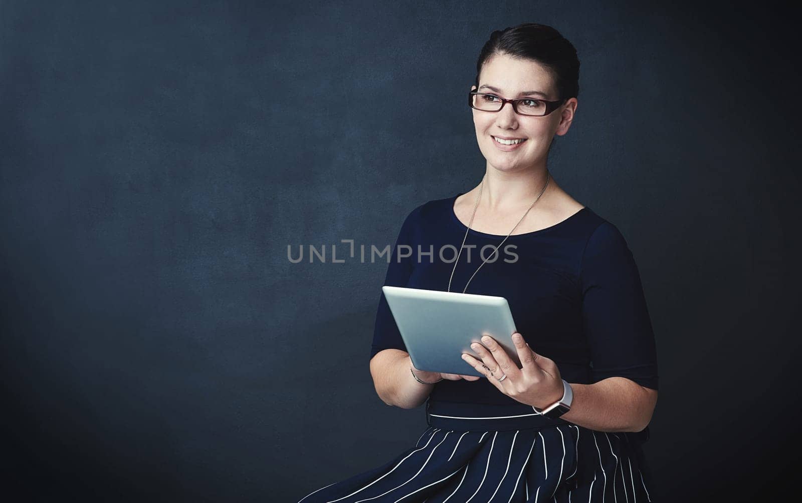 Innovation is always on her mind. Studio portrait of a corporate businesswoman using a digital tablet against a dark background. by YuriArcurs