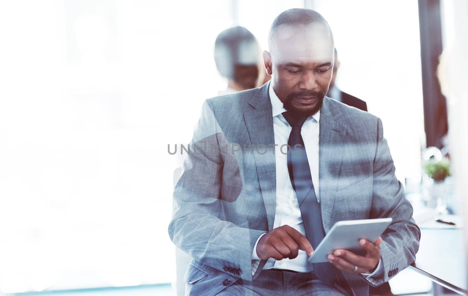 The ideal device to compliment his professional needs. a businessman using a digital tablet during a meeting at work