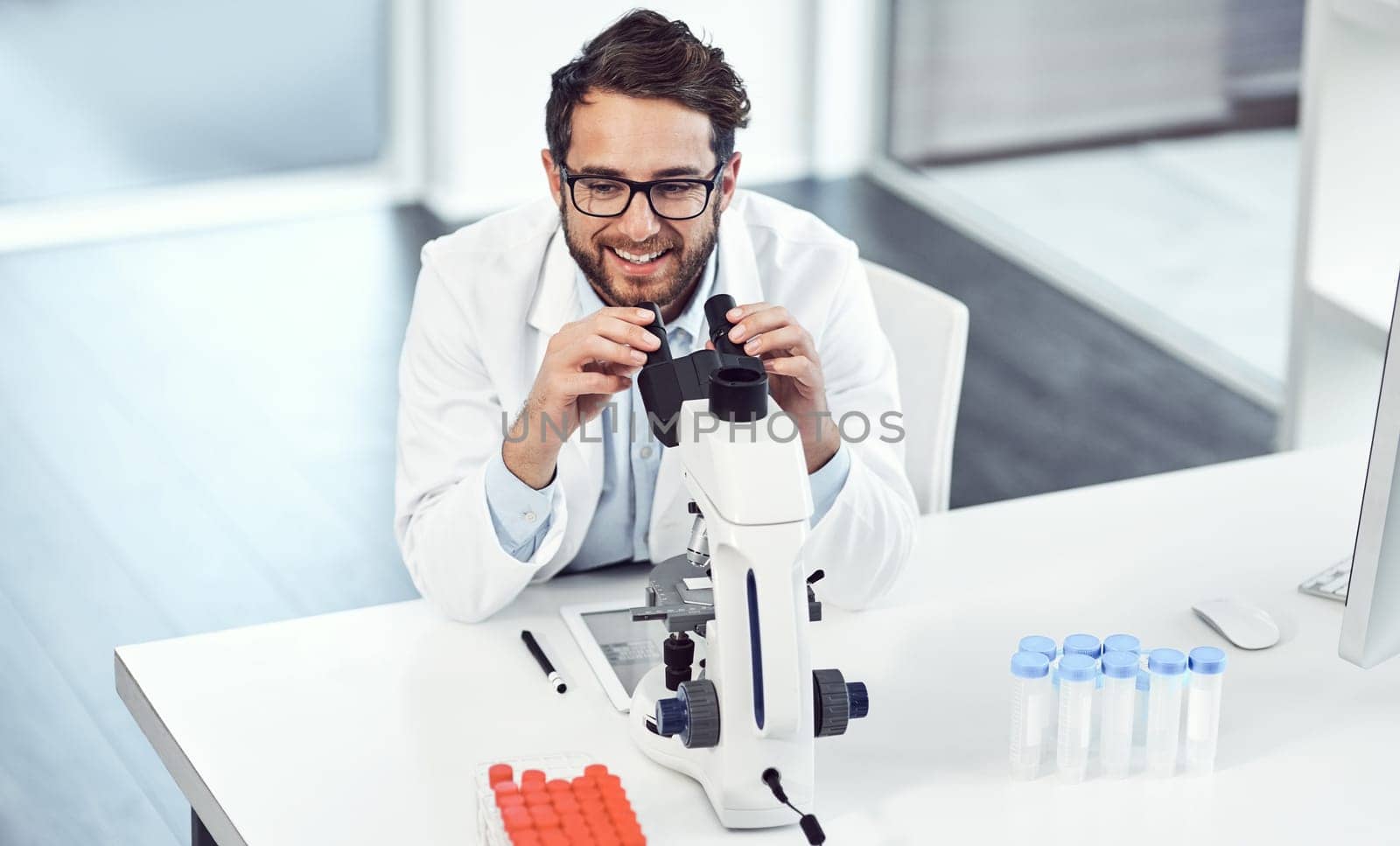 I have a good feeling about these formulas. a cheerful young male scientist looking through a microscope inside of a laboratory. by YuriArcurs