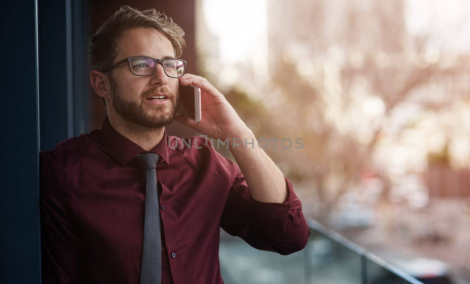 Every call brings him closer to success. a young businessman using a mobile phone on the balcony of an office