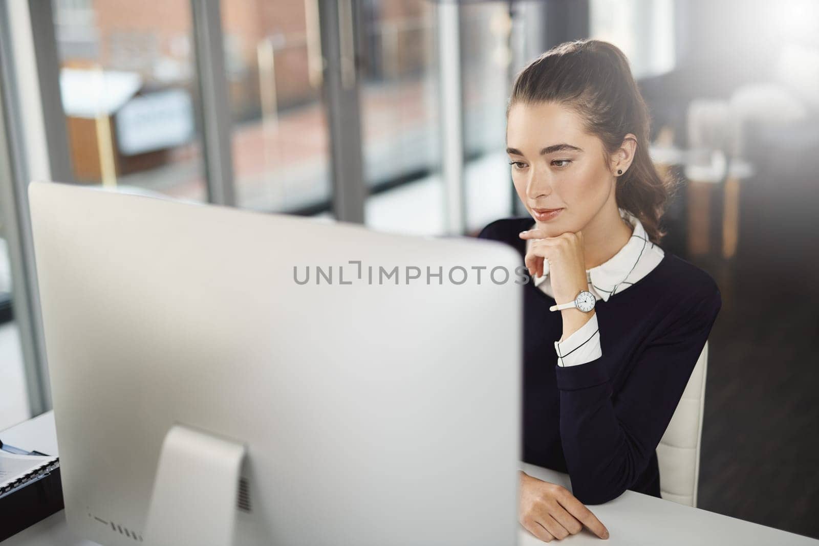 There are new things to learn everyday. an attractive young businesswoman sitting at her desk and looking at her computer screen in a modern office. by YuriArcurs
