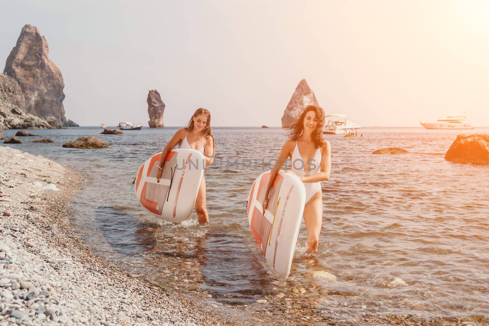 Woman sup yoga. Middle age sporty woman practising yoga pilates on paddle sup surfboard. Female stretching doing workout on sea water. Modern individual hipster outdoor summer sport activity