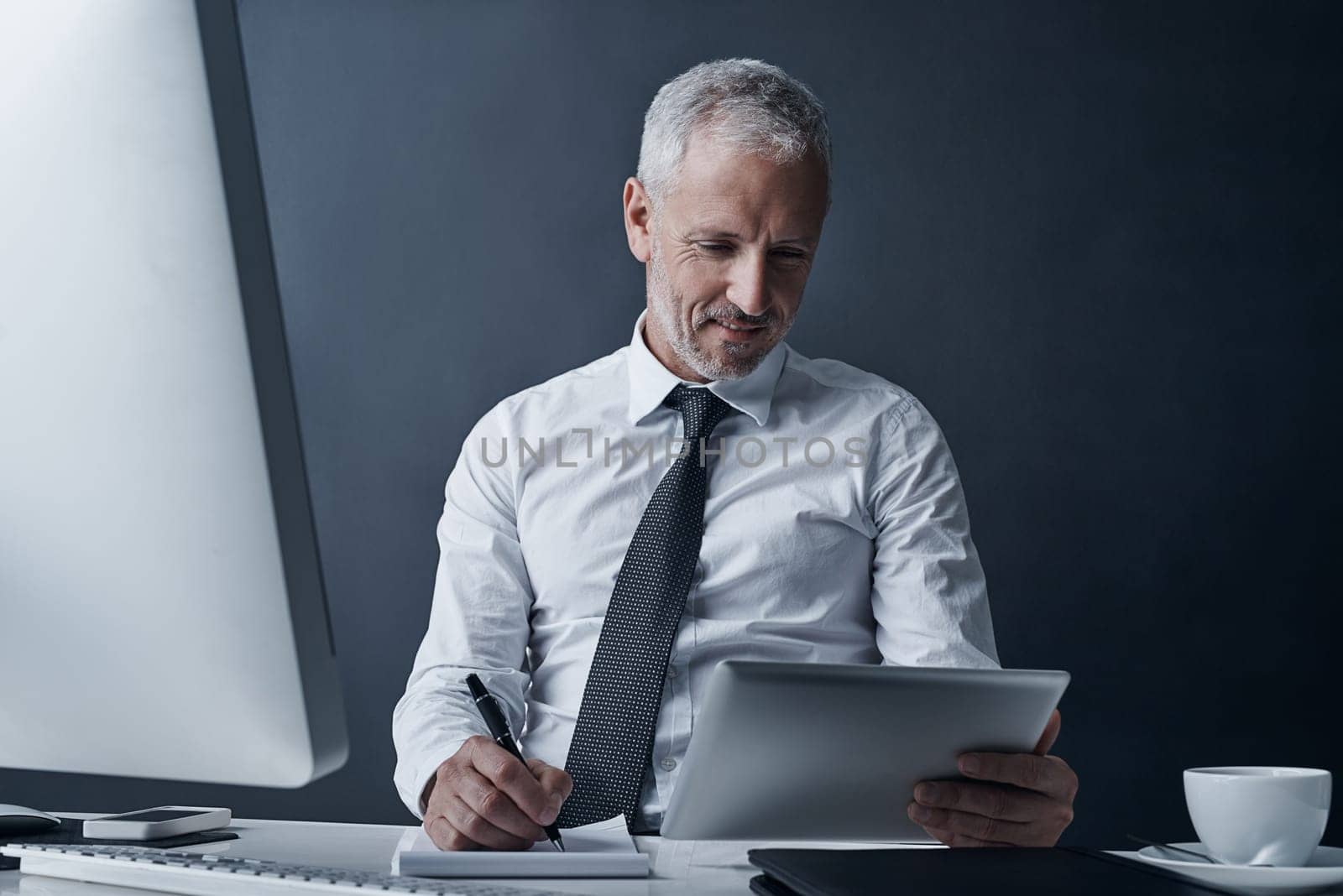 Thats worth making a note. a mature businessman working on his tablet