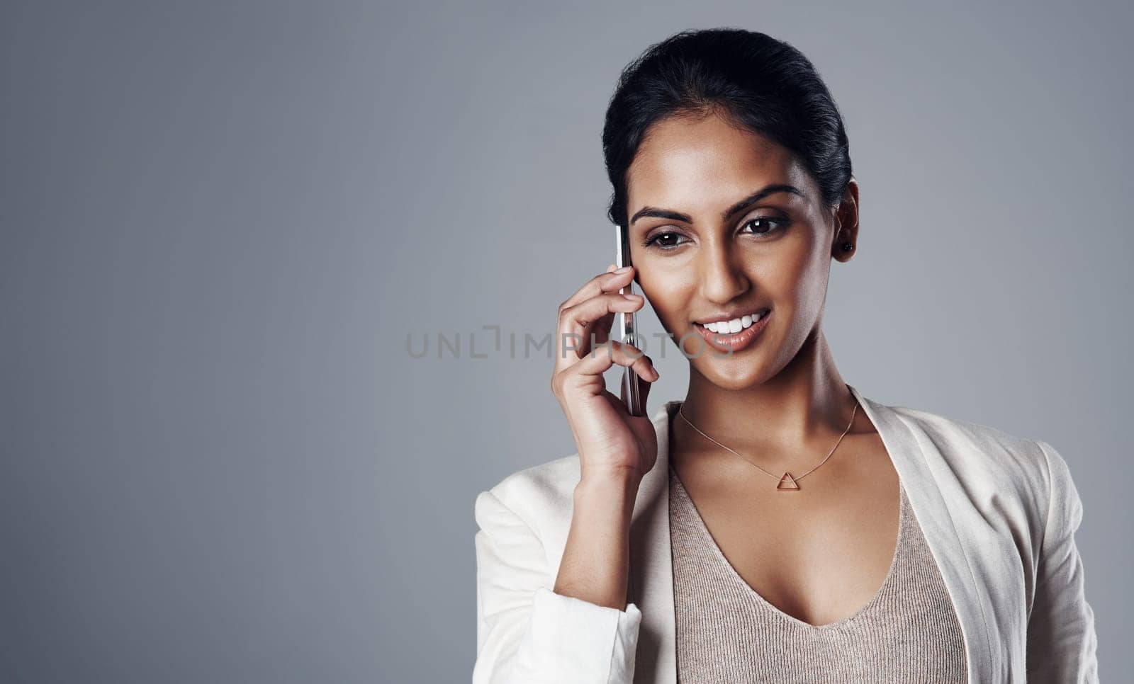 Connecting with other business minded people. Studio shot of a young businesswoman using a phone against a gray background