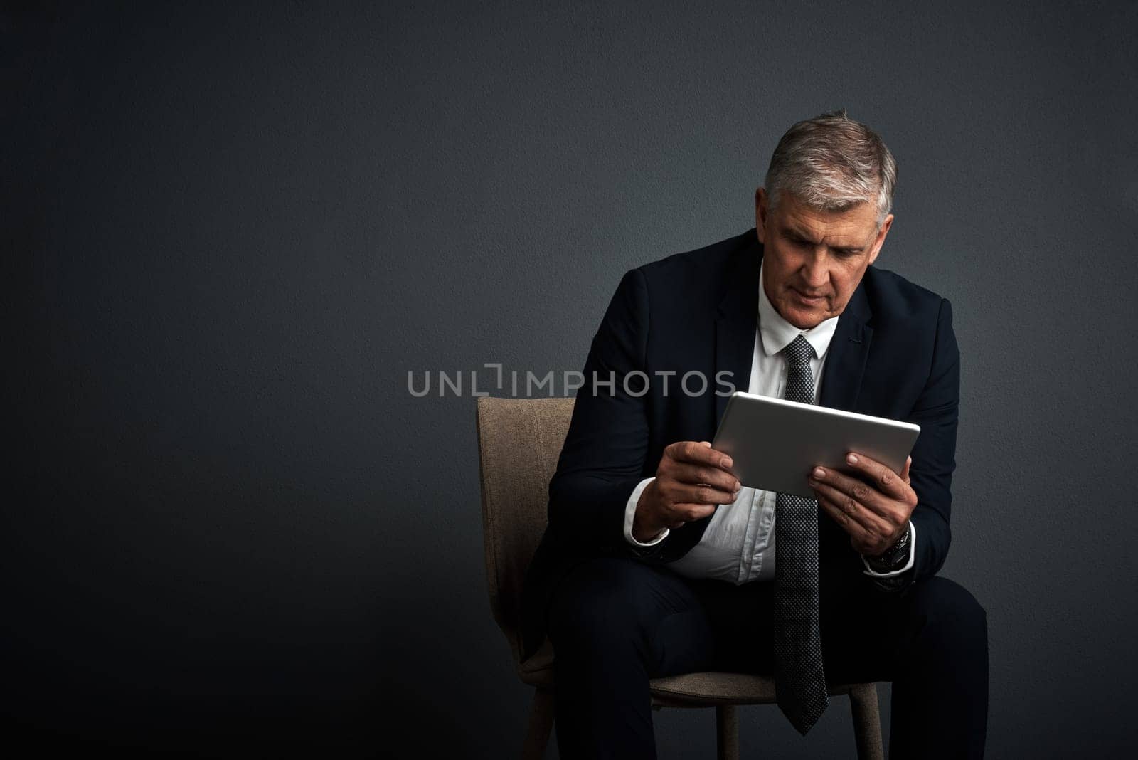 You create your own road map to success. Studio shot of a mature businessman using his digital tablet. by YuriArcurs
