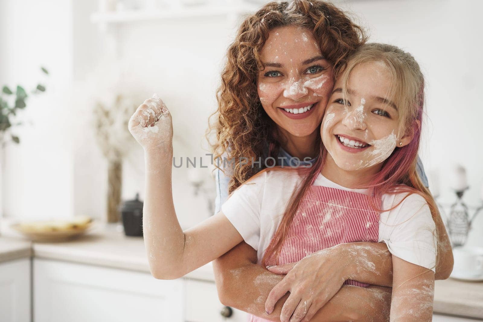 Mother and daughter having fun while cooking dough in kitchen by Fabrikasimf