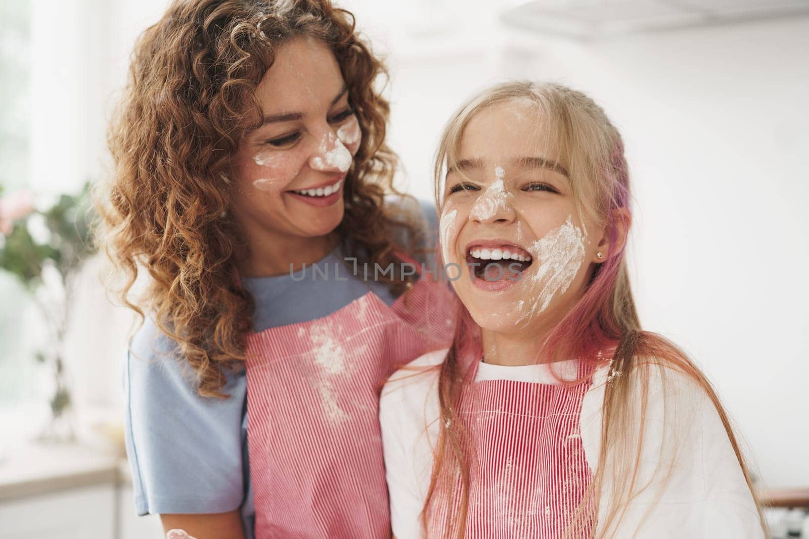 Mother and daughter having fun while cooking dough in kitchen by Fabrikasimf